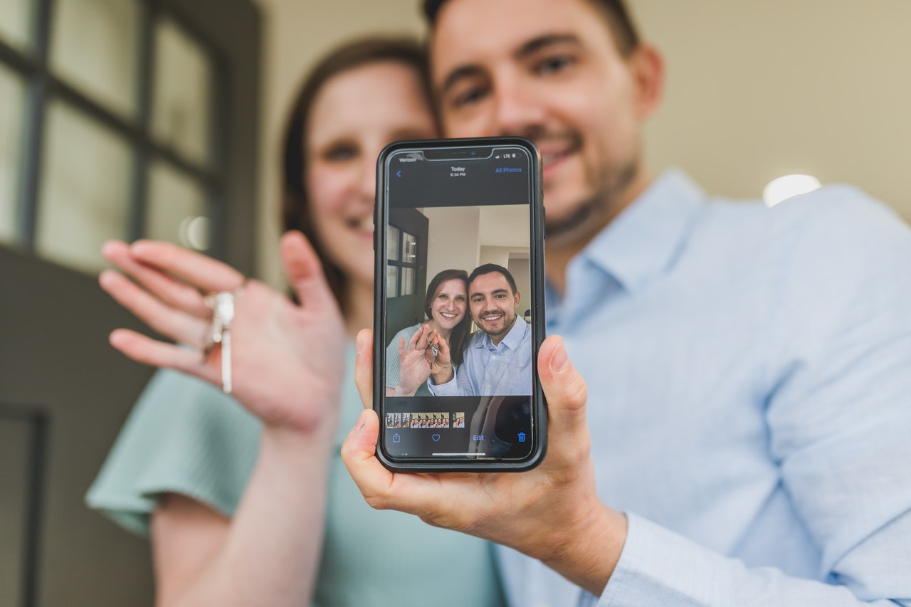 Foto de una pareja tomándose una selfie con mostrando las llaves de su apartamento nuevo. by RODNAE Productions from Pexels